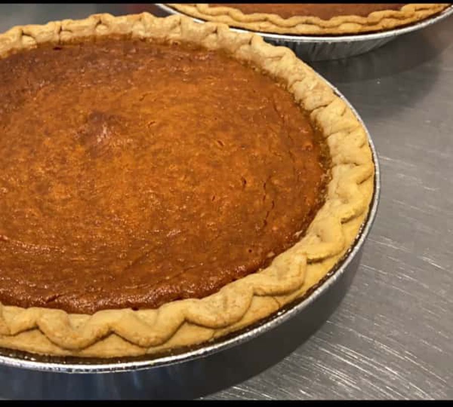 Two pumpkin pies are sitting on a table.