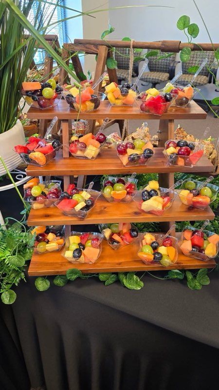 Fruit cups on a wooden tiered display, with various fruits like grapes, watermelon, and berries.