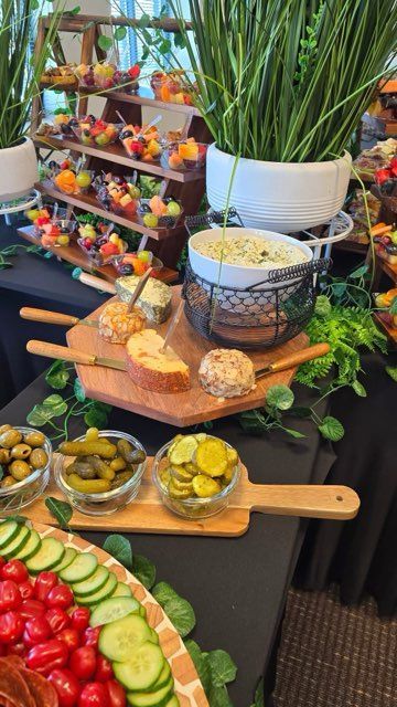 A table laden with appetizers: cheeses, fruits, pickles, and dips arranged for display and consumption.