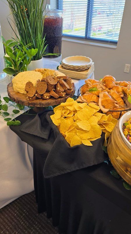 Food buffet table with various dishes: chips, dips, bread, and drinks.