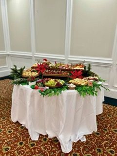 Buffet table with food displays, decorated for the holidays with greenery and flowers.