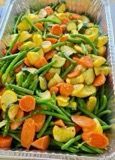 Vegetable medley in a metal pan, including green beans, carrots, and yellow squash.