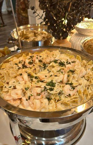 Pasta dish with shrimp in a metal serving dish, part of a buffet.