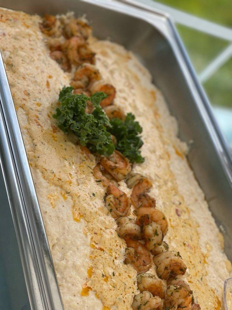 Shrimp and grits in a metal serving tray, garnished with parsley.