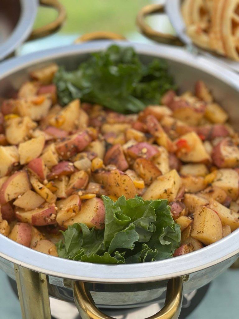Red potato hash in a silver chafing dish, garnished with green lettuce.