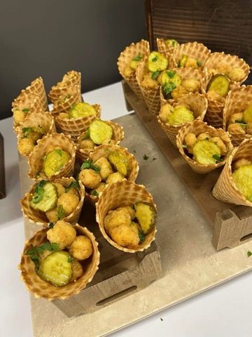 A tray of ice cream cones filled with food on a table.
