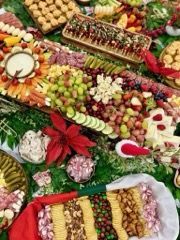 A large, colorful food spread including fruits, cheeses, crackers, and appetizers on a green surface.