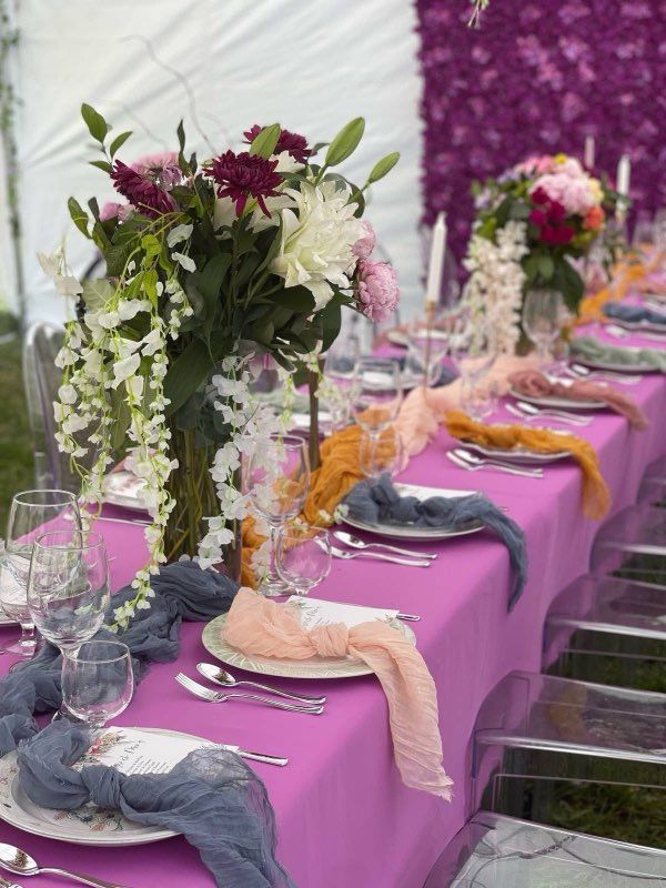 Festive table setting with magenta tablecloth, floral centerpieces, and pastel napkins.