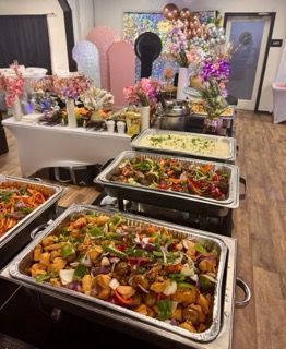 Buffet with various dishes on display, decorated with flowers and balloons.