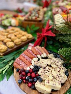 Charcuterie board with salami, cheese, berries, and nuts, arranged on a wooden platter with greenery.