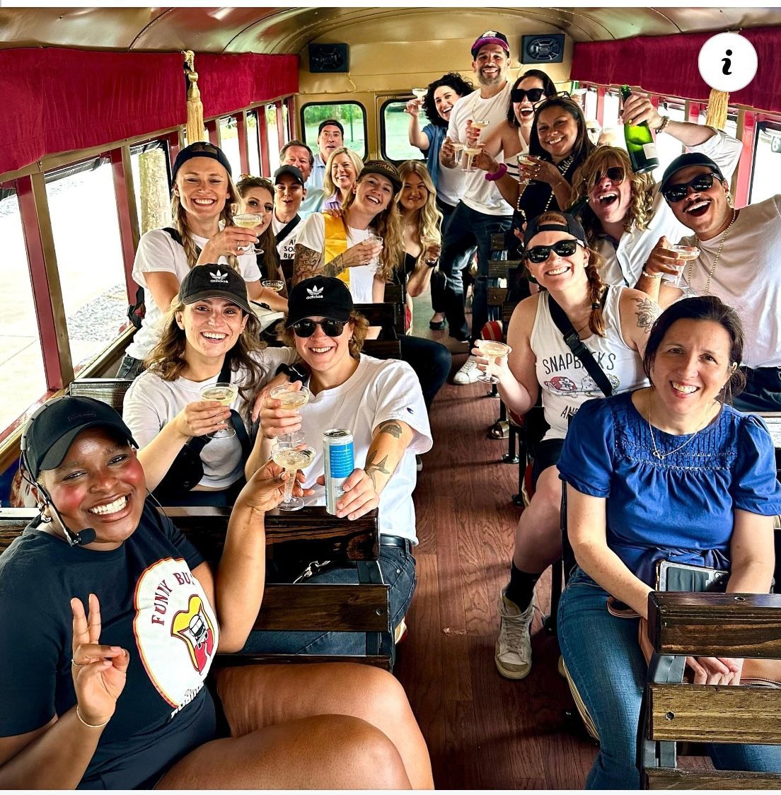 Group of friends smiling inside a vintage train car, holding drinks and posing together.