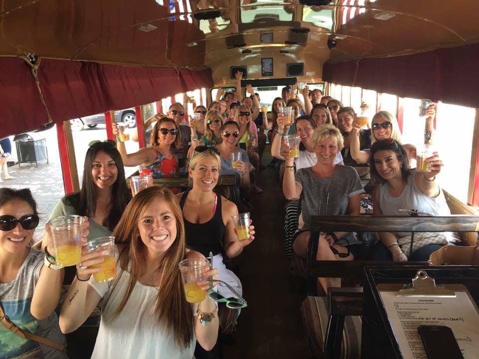 Friends toasting cans of beer and laughing together on a party bus