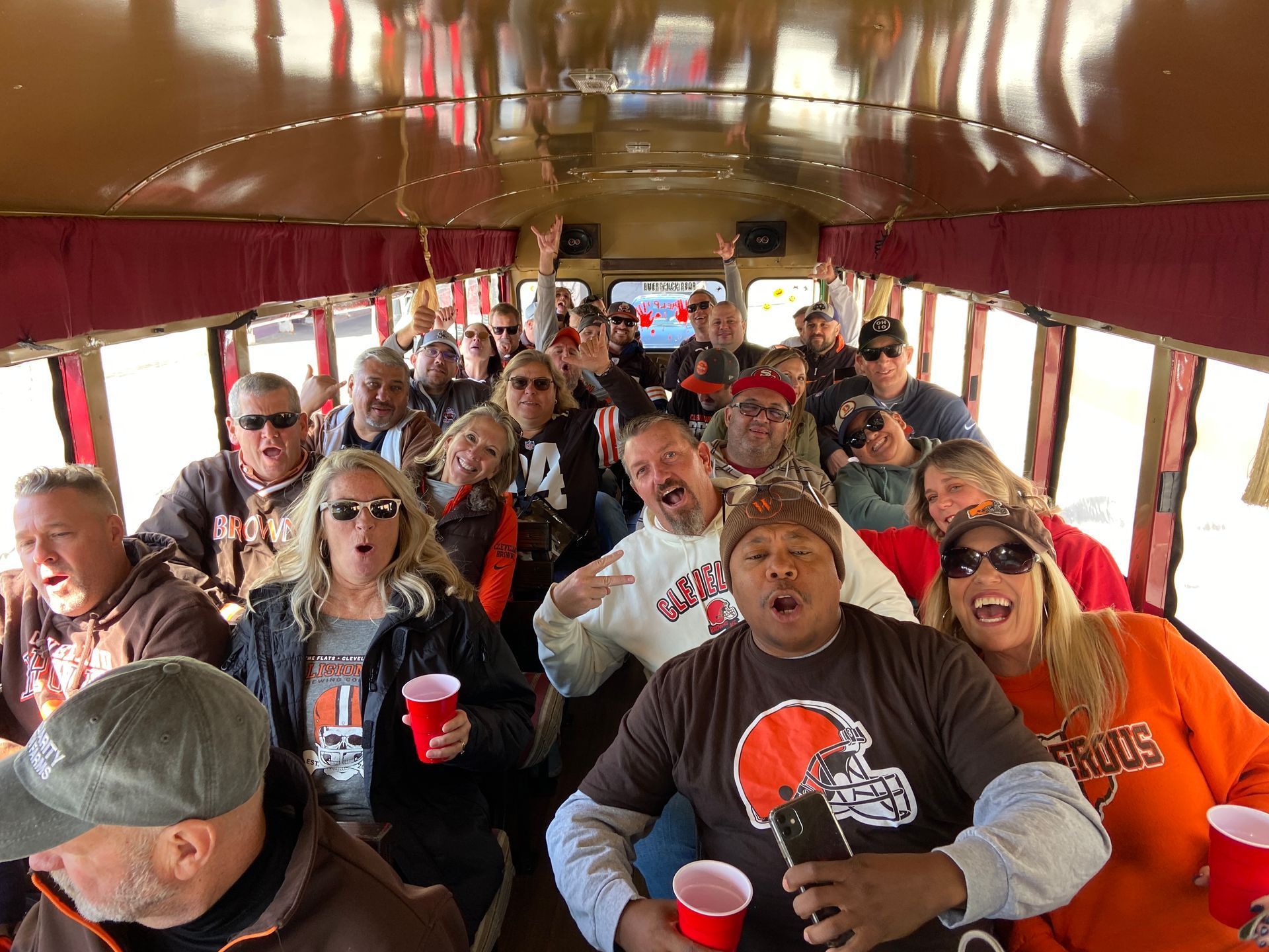 Crowd of people inside a red trolley, cheering and holding red cups.