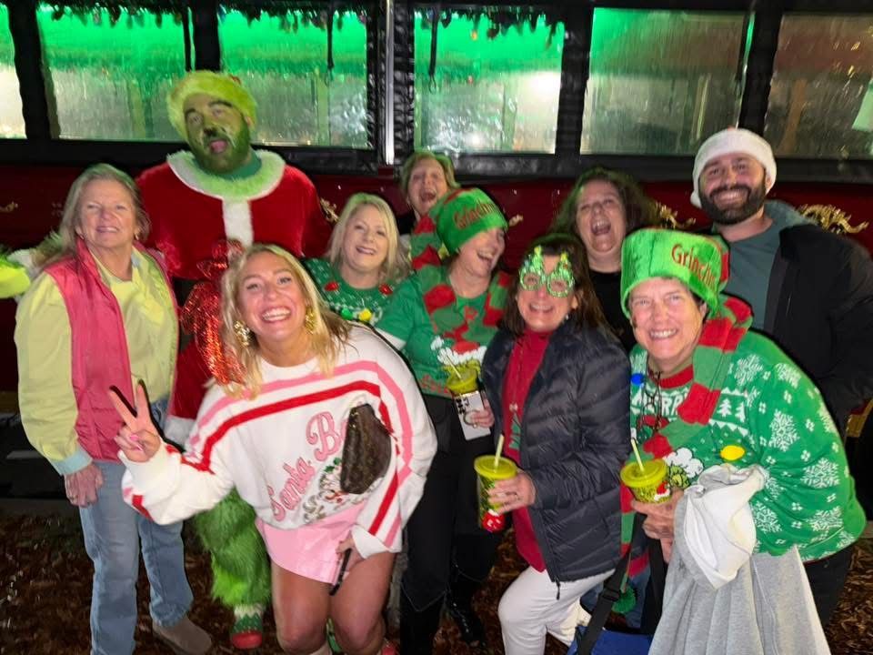 Group of people smiling and posing in colorful St. Patrick’s Day outfits at a festive bar scene