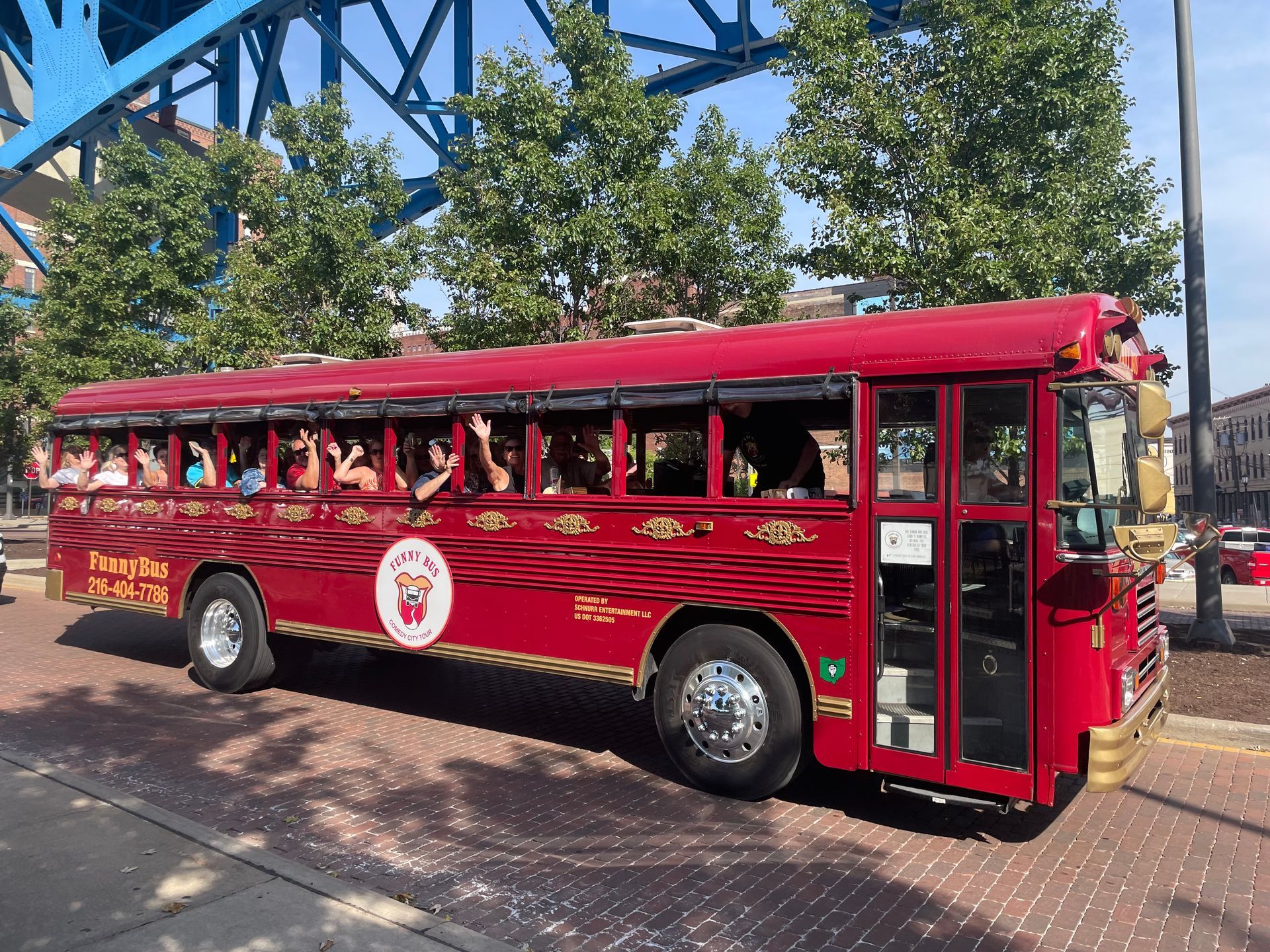 Red trolley tour bus parked on a street with passengers visible through the windows