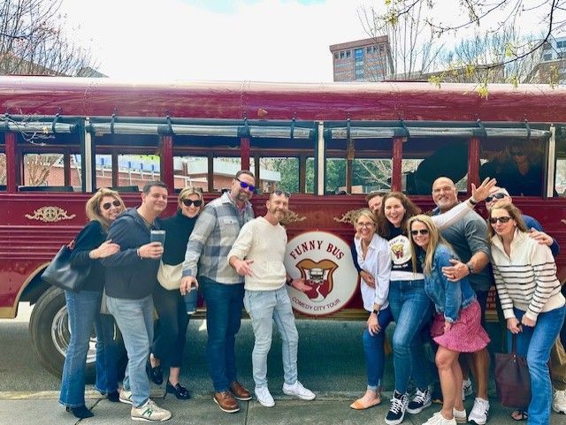 Group of Funny Bus guests posing at the red comedy tour bus