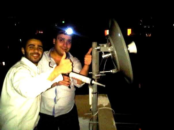 Fadi Helou – Wireless Link Setup in Beirut, 2006 Fadi Helou and team installing a long-range wireless bridge on a rooftop in Beirut, 2006 – early ISP infrastructure setup at night.