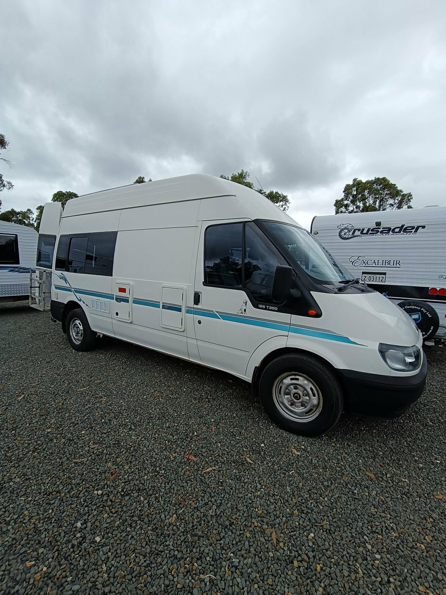 White Campervan With Teal Stripe Parked on Gravel — Great Lakes Caravans & RV P/L In Nabiac, NSW