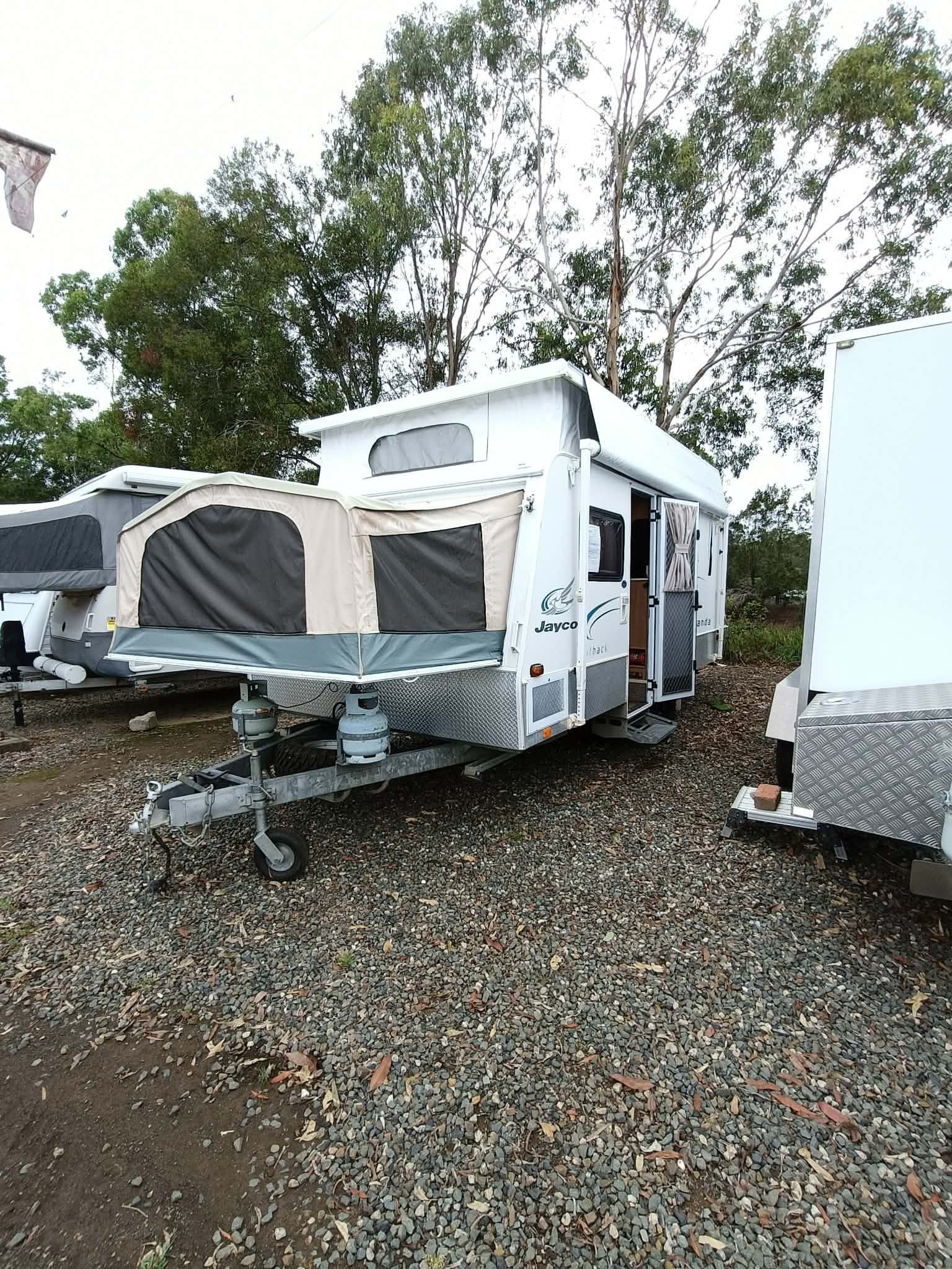 White camper trailer with front awning parked on gravel near trees — Great Lakes Caravans & RV P/L In Port Macquarie, NSW