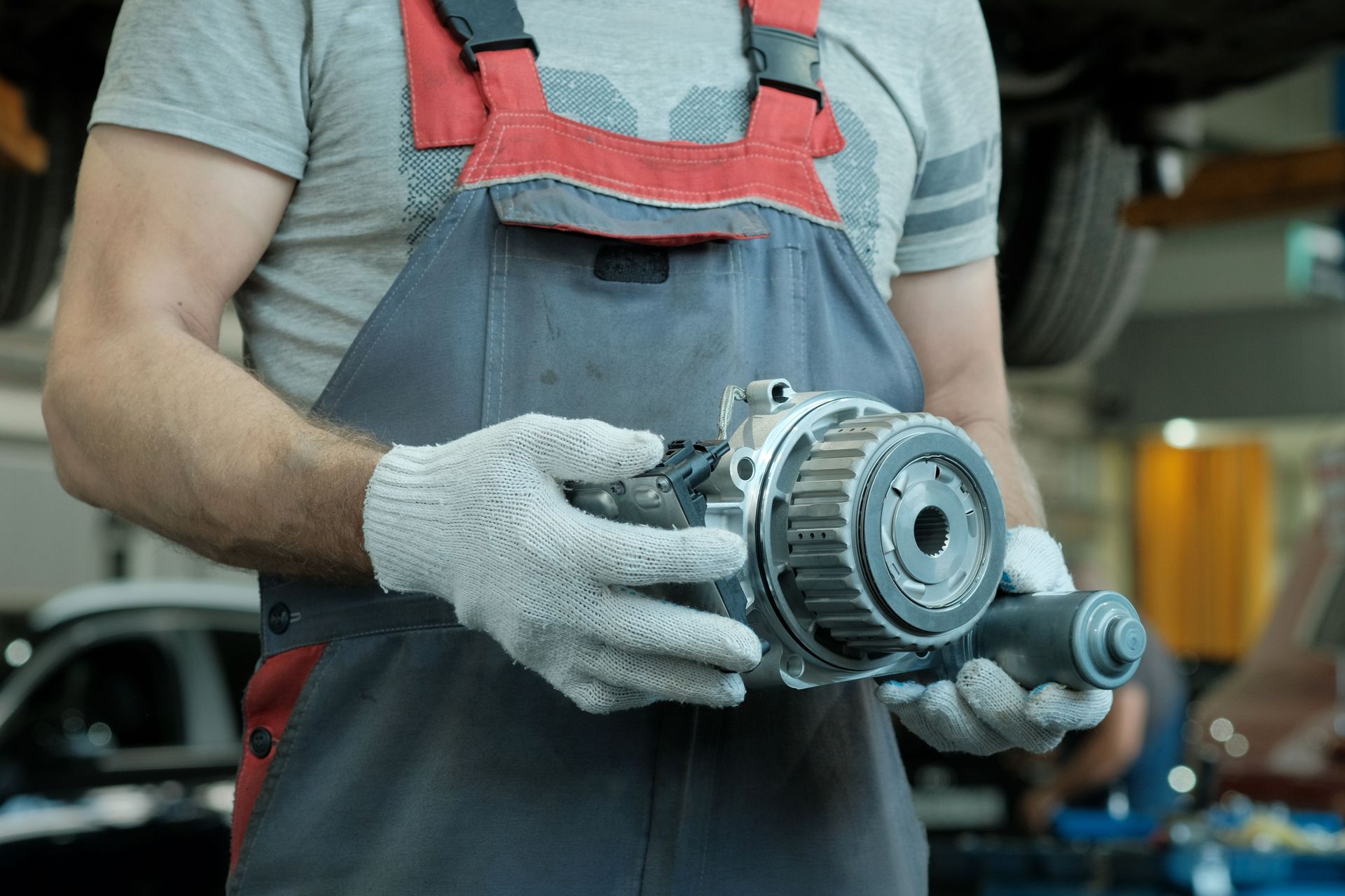 A mechanic's hands are holding a gearbox to perform an auto transmission replacement service. A mechanic's hands are holding a gearbox to perform an auto transmission replacement service.