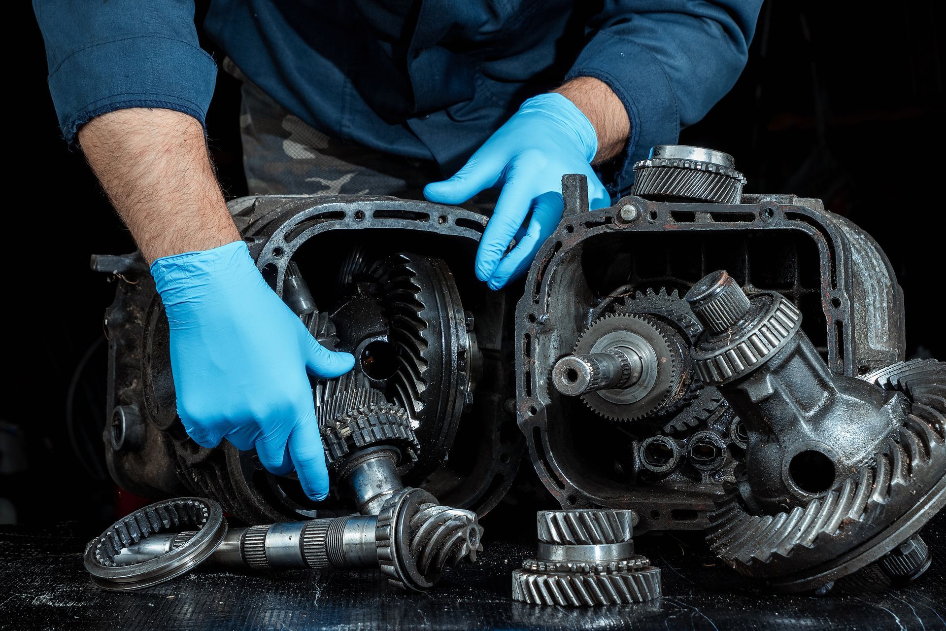 Close-up of a mechanic in blue gloves, touching a gearbox, for gearbox repair service. Close-up of a mechanic in blue gloves, touching a gearbox, for gearbox repair service.