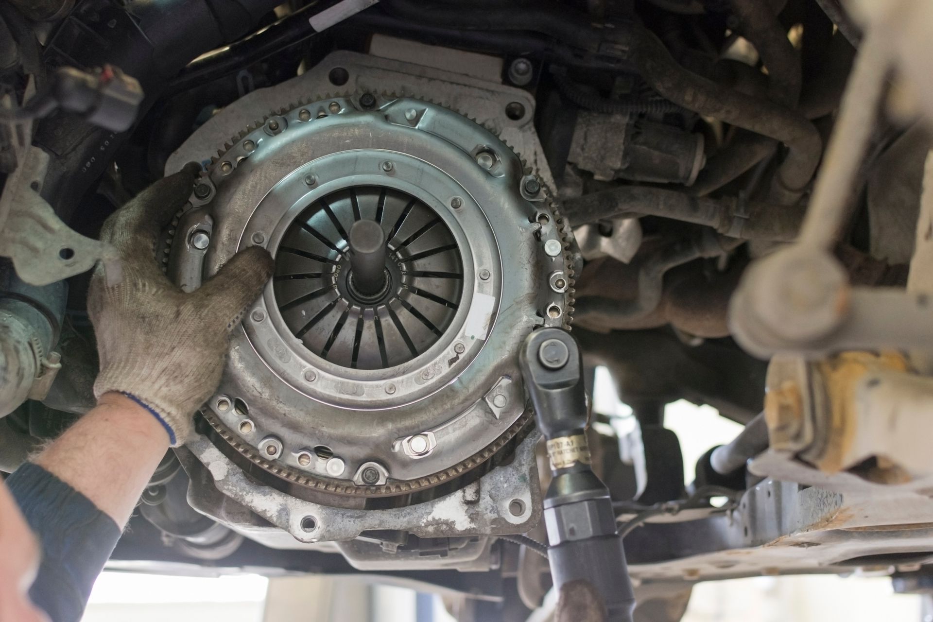 Mechanic's hands performing an auto transmission replacement, replacing the clutch disc.