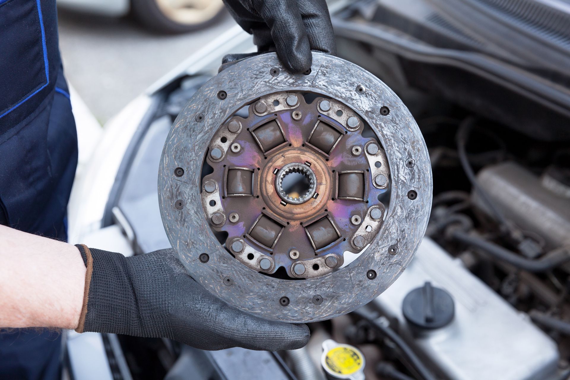 A Mechanic Wearing Protective Work Gloves Holds Old Clutch Discover a Car Engine | Canberra, Act | Auto Drive Transmission A Mechanic Wearing Protective Work Gloves Holds Old Clutch Discover a Car Engine | Canberra, Act | Auto Drive Transmission