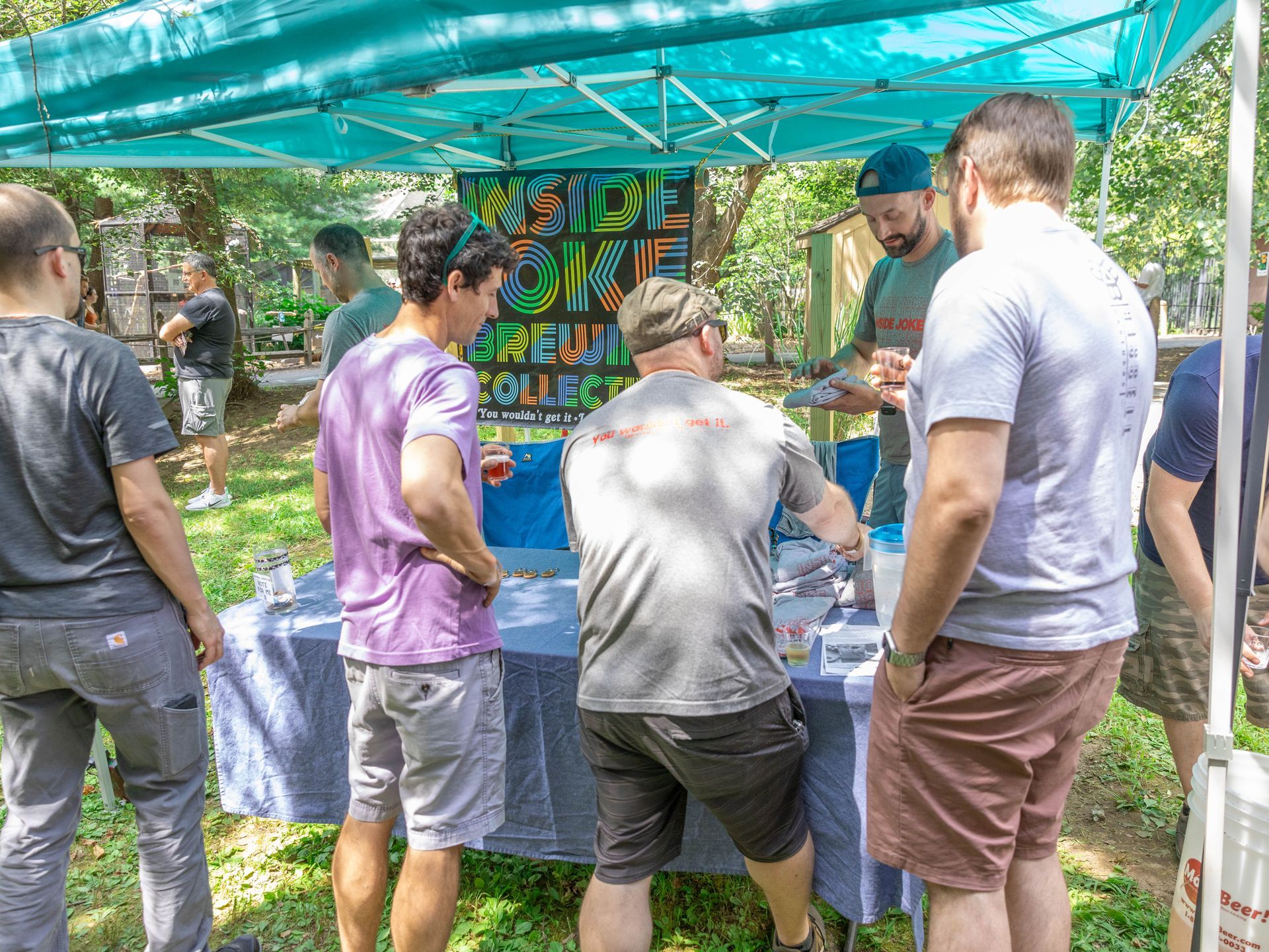 Three men try beer from a home brewer's table. 