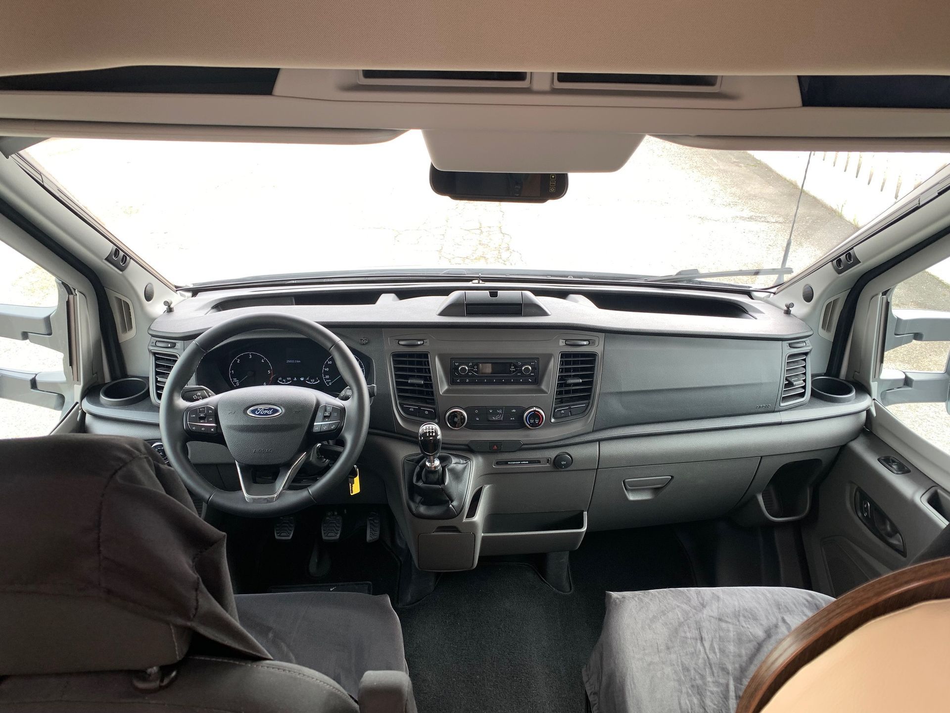 Vista interna dell'auto dal sedile posteriore, che mostra il cruscotto, il volante e i sedili anteriori.