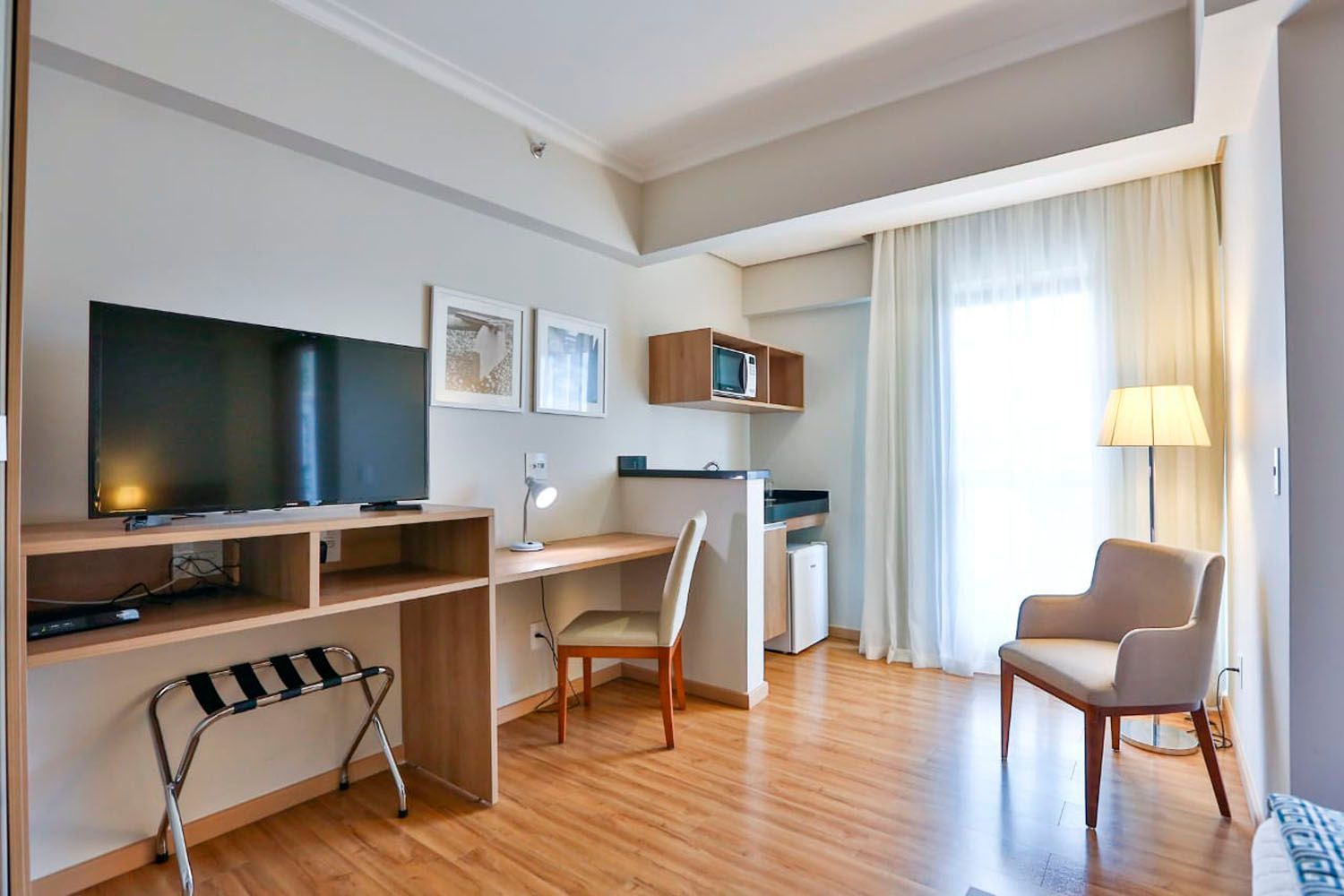 Um quarto de hotel com uma mesa, cadeira e televisão.
