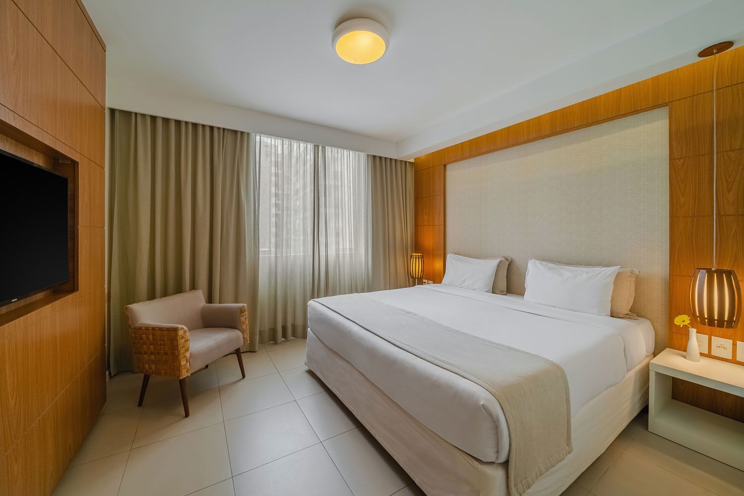 Um quarto de hotel com uma cama king size, cadeira e televisão.