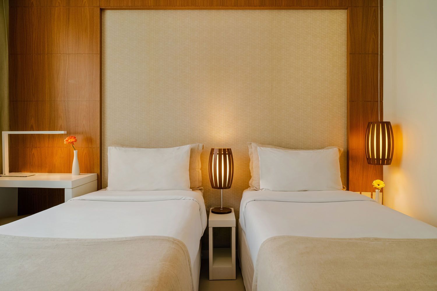 Um quarto de hotel com duas camas e duas lâmpadas.