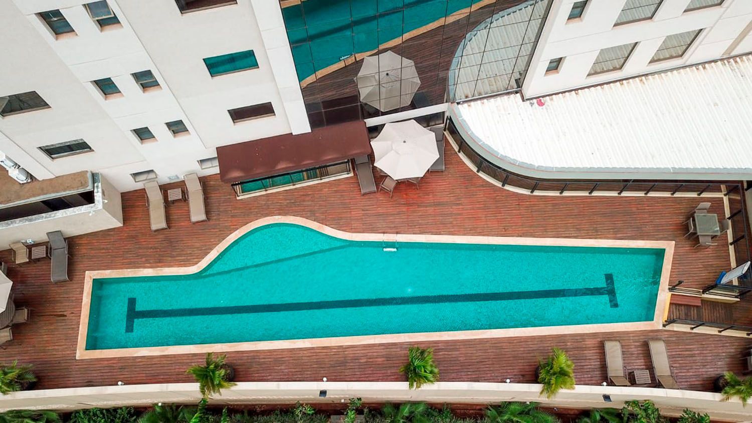 Uma vista aérea de uma grande piscina em frente a um edifício.