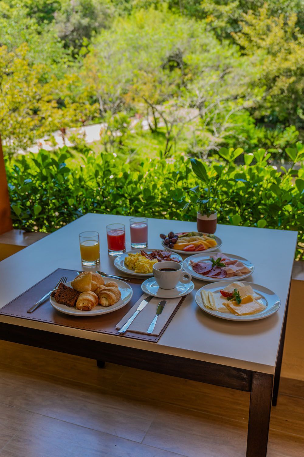 Uma mesa coberta com pratos de comida e bebidas em frente a uma janela.