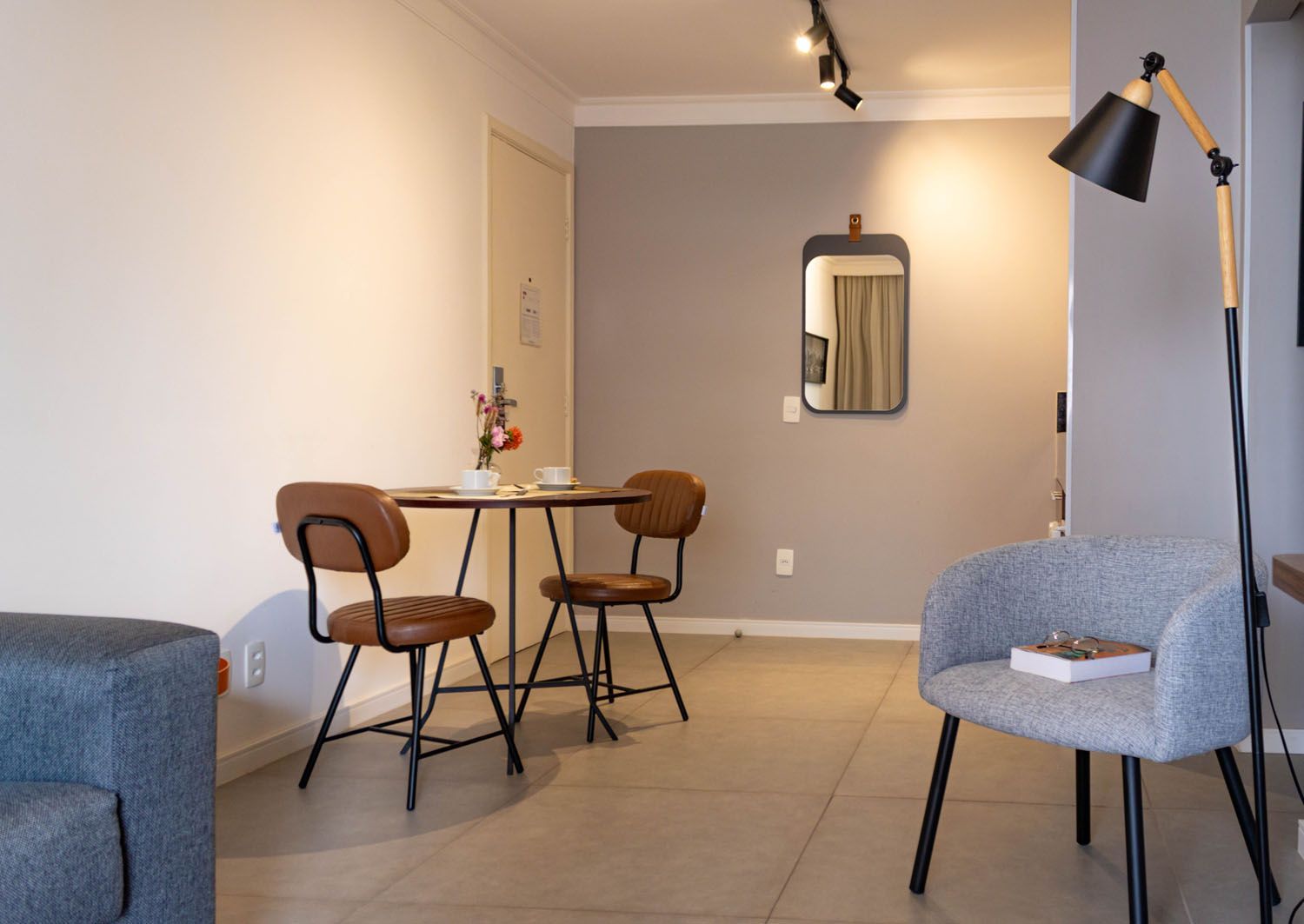 Uma sala de estar com uma mesa, cadeiras e um abajur.