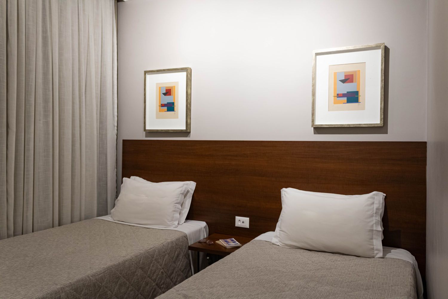 Um quarto de hotel com duas camas e duas pinturas na parede