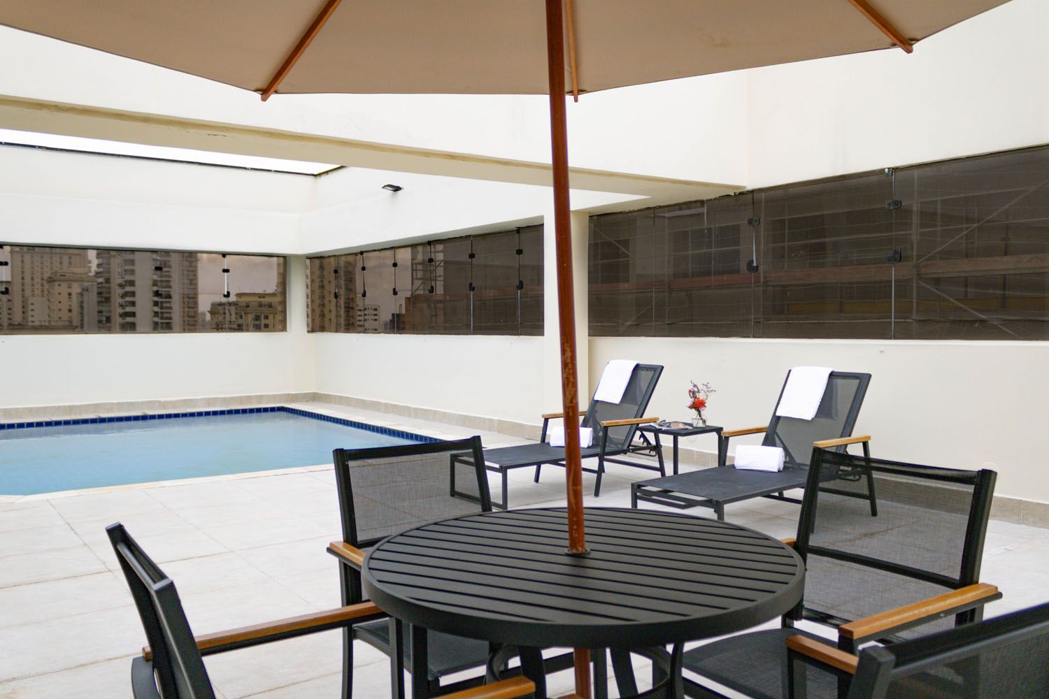 Uma mesa e cadeiras sob um guarda-sol ao lado de uma piscina