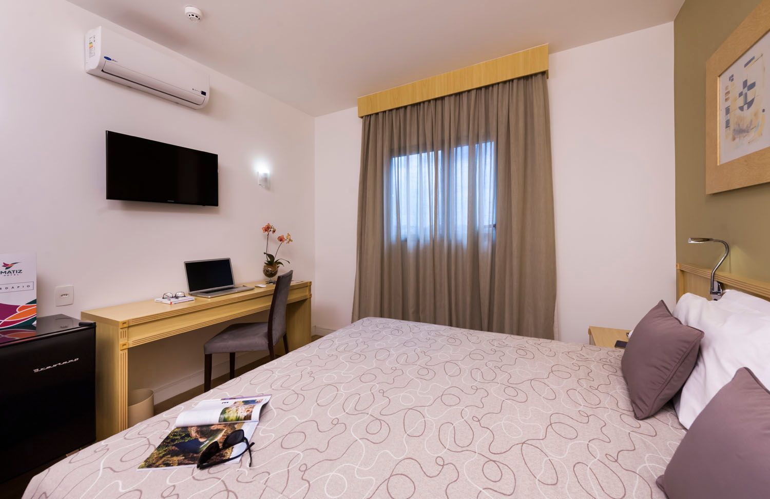 Um quarto de hotel com uma cama king size, escrivaninha e televisão.