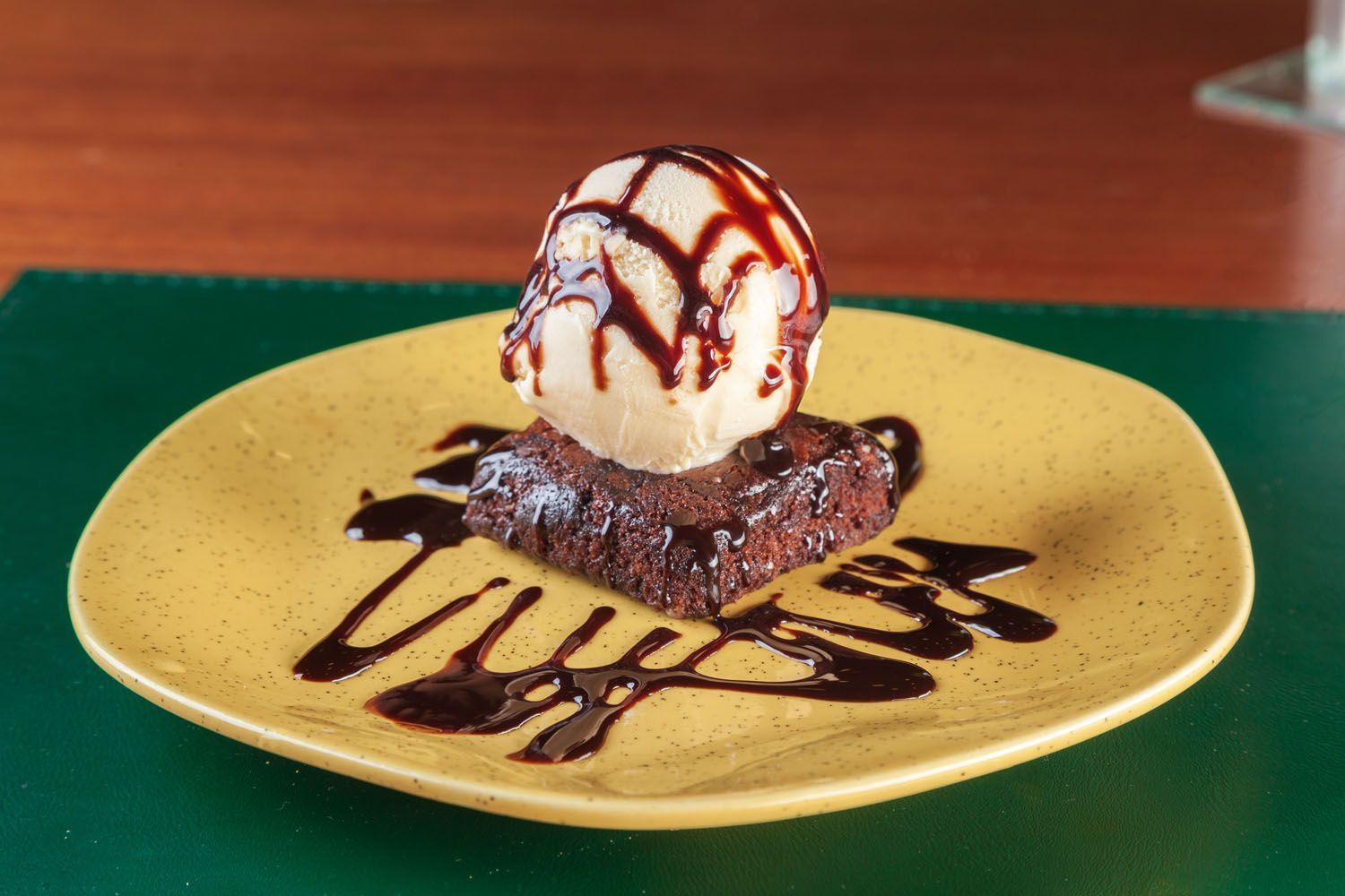 Um brownie com sorvete por cima em um prato amarelo