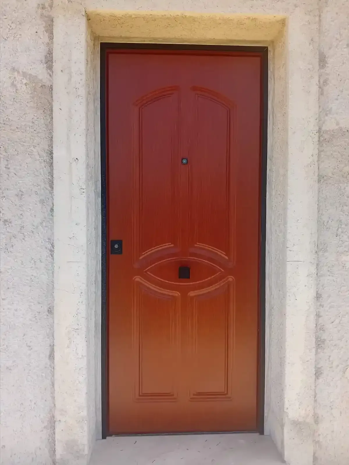 Porta rossa con un disegno a forma di occhio incastonato in una cornice di cemento.