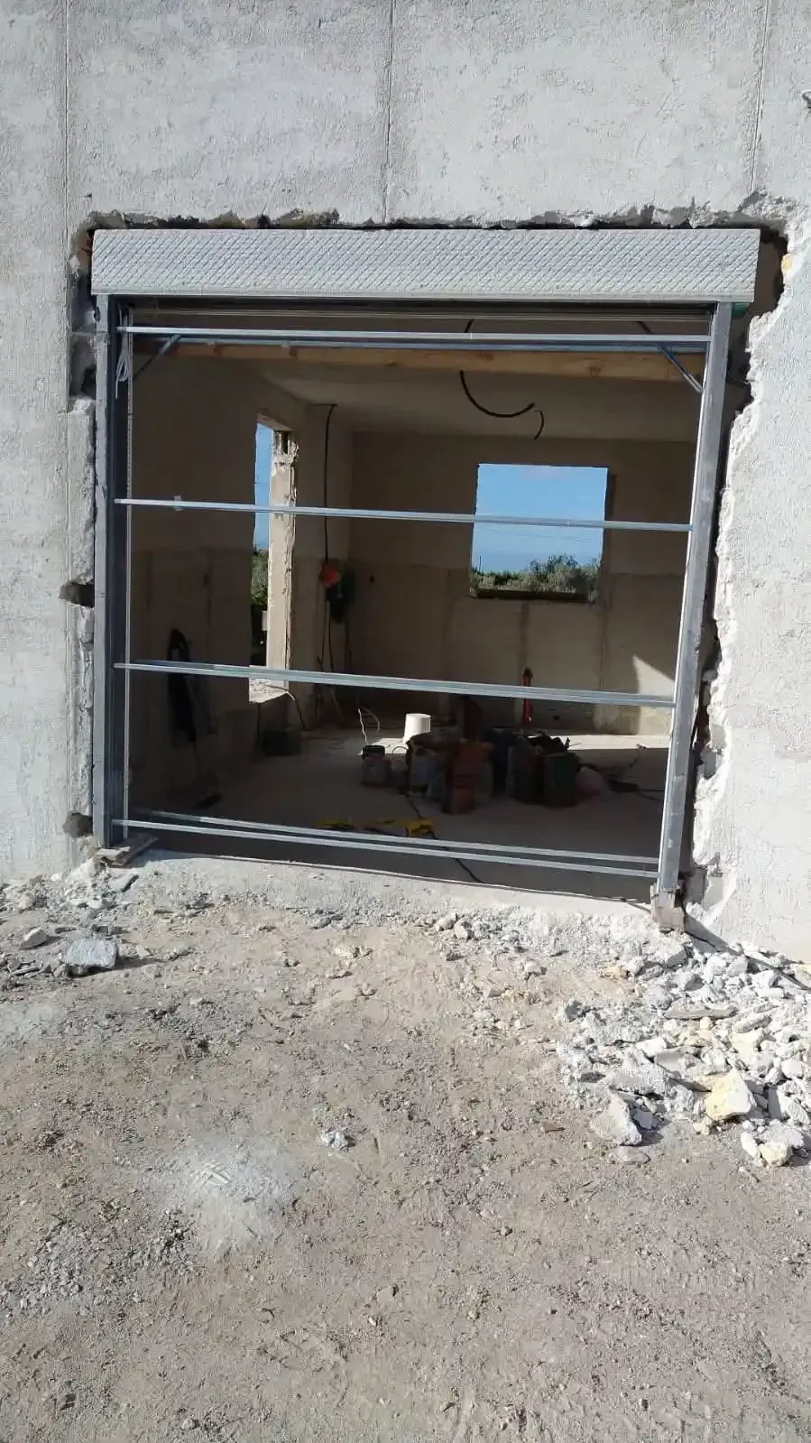Una saracinesca di sicurezza in metallo in un'apertura grezza di un edificio in costruzione, che ne mostra l'interno.