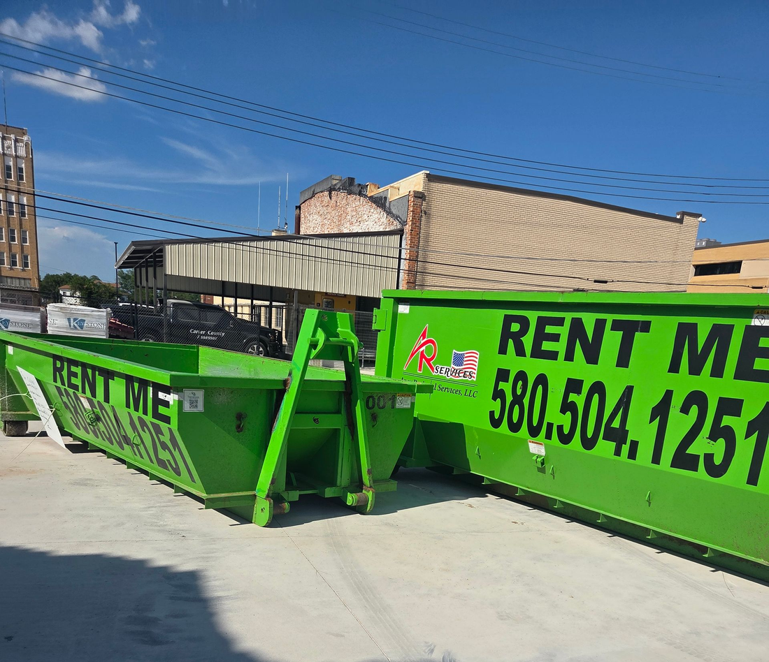 Green dumpsters on a paved surface with