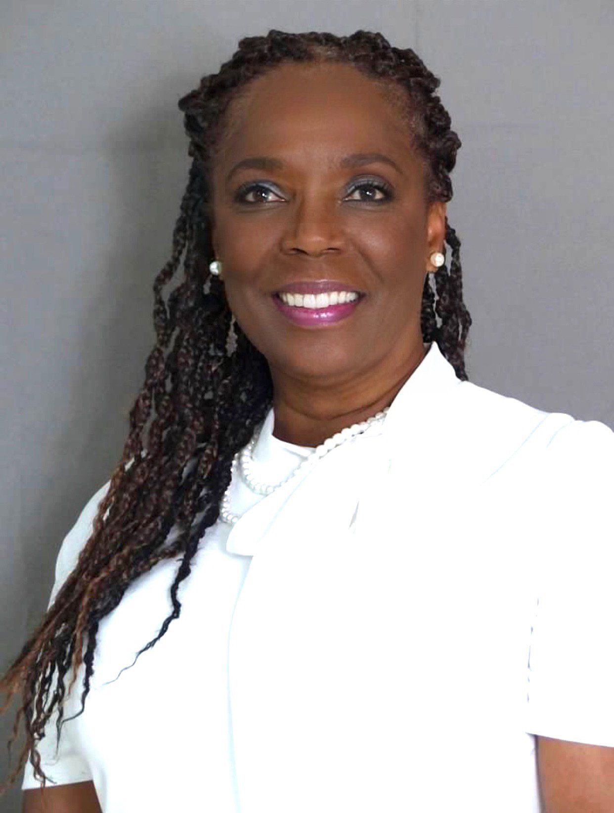 A woman with braids is wearing a white shirt and smiling