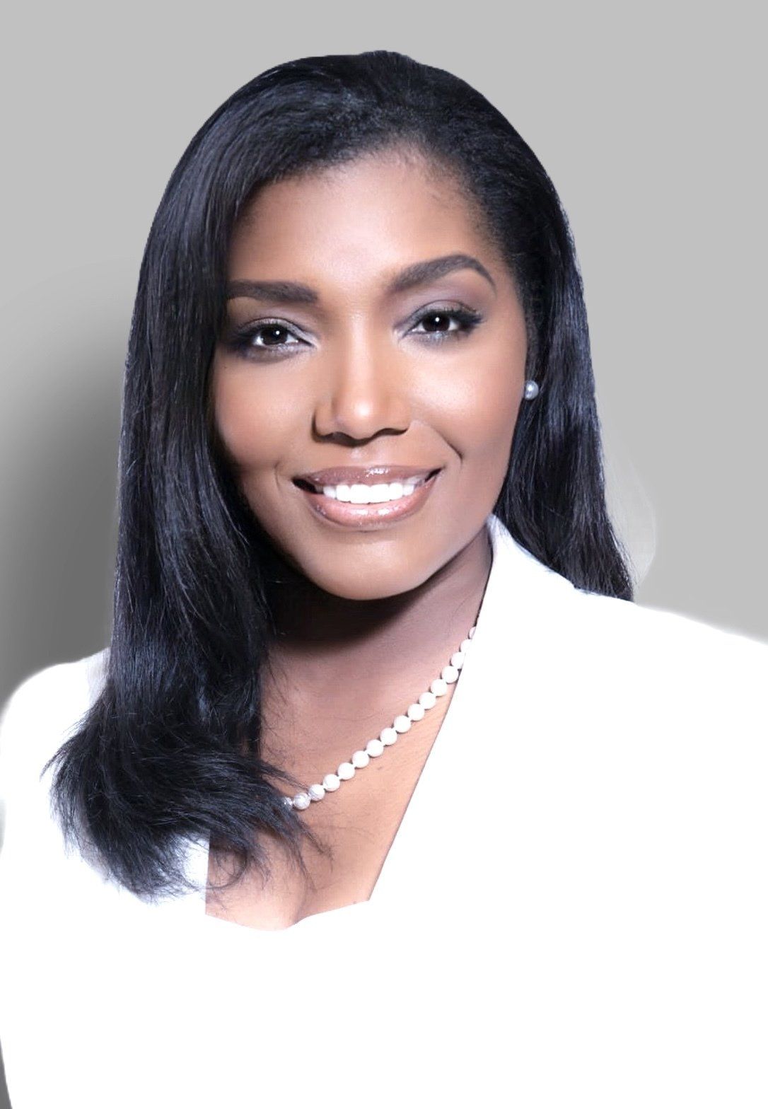 A woman wearing a white jacket and a pearl necklace smiles for the camera.