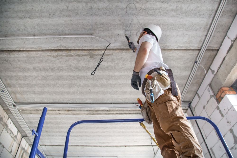 A Man Is Standing On A Scaffolding Working On A Ceiling — Cairns Excel Electrics In Mount Sheridan, QLD