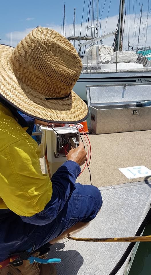 A Man Wearing A Straw Hat Is Working On A Boat — Cairns Excel Electrics In Bungalow, QLD