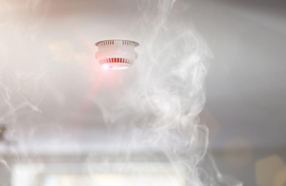 A Smoke Detector On The Ceiling With Smoke Coming Out Of It — Cairns Excel Electrics In Whitfield, QLD