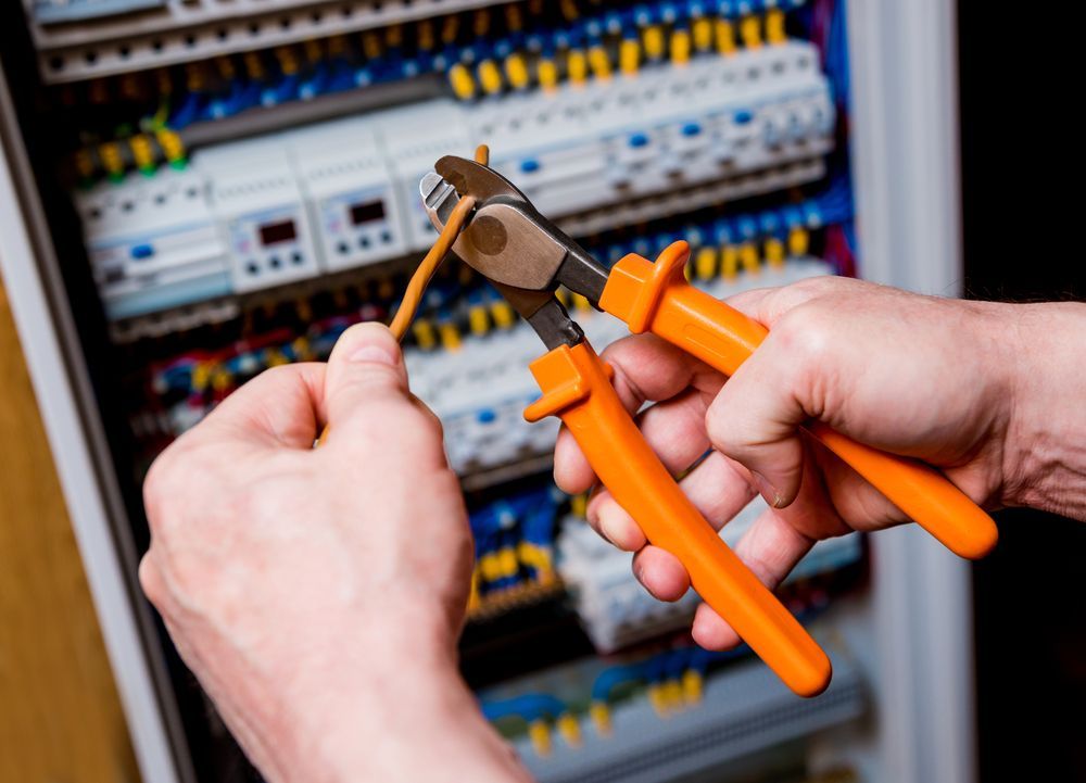 A Person Is Cutting A Wire With A Pair Of Pliers — Cairns Excel Electrics In Freshwater, QLD