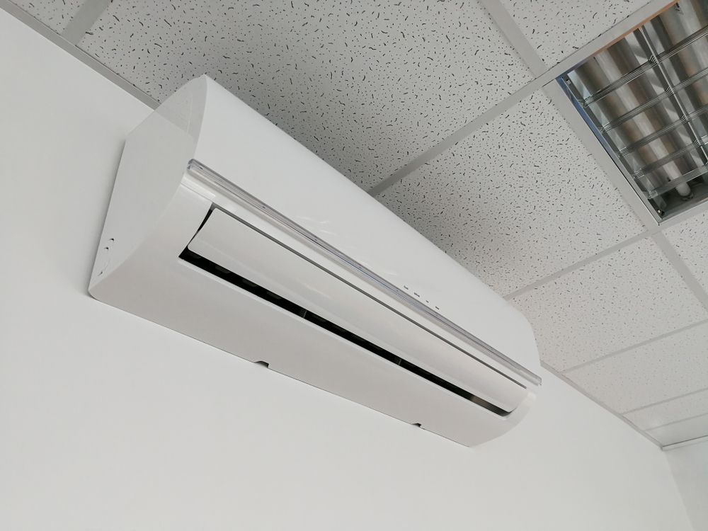 A White Air Conditioner Is Mounted To A White Wall — Cairns Excel Electrics In Bungalow, QLD