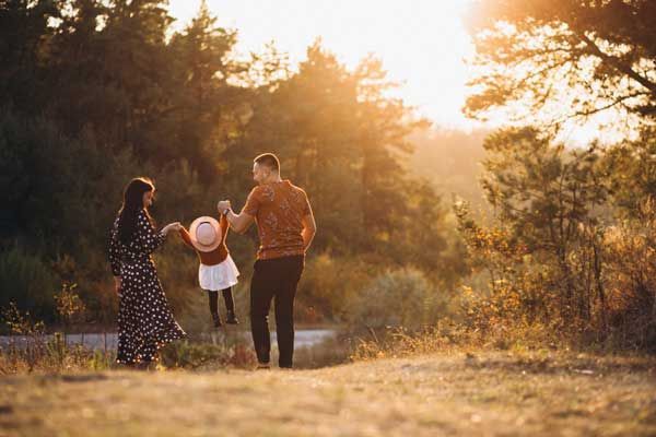 Eine Familie geht bei Sonnenuntergang im Wald spazieren.